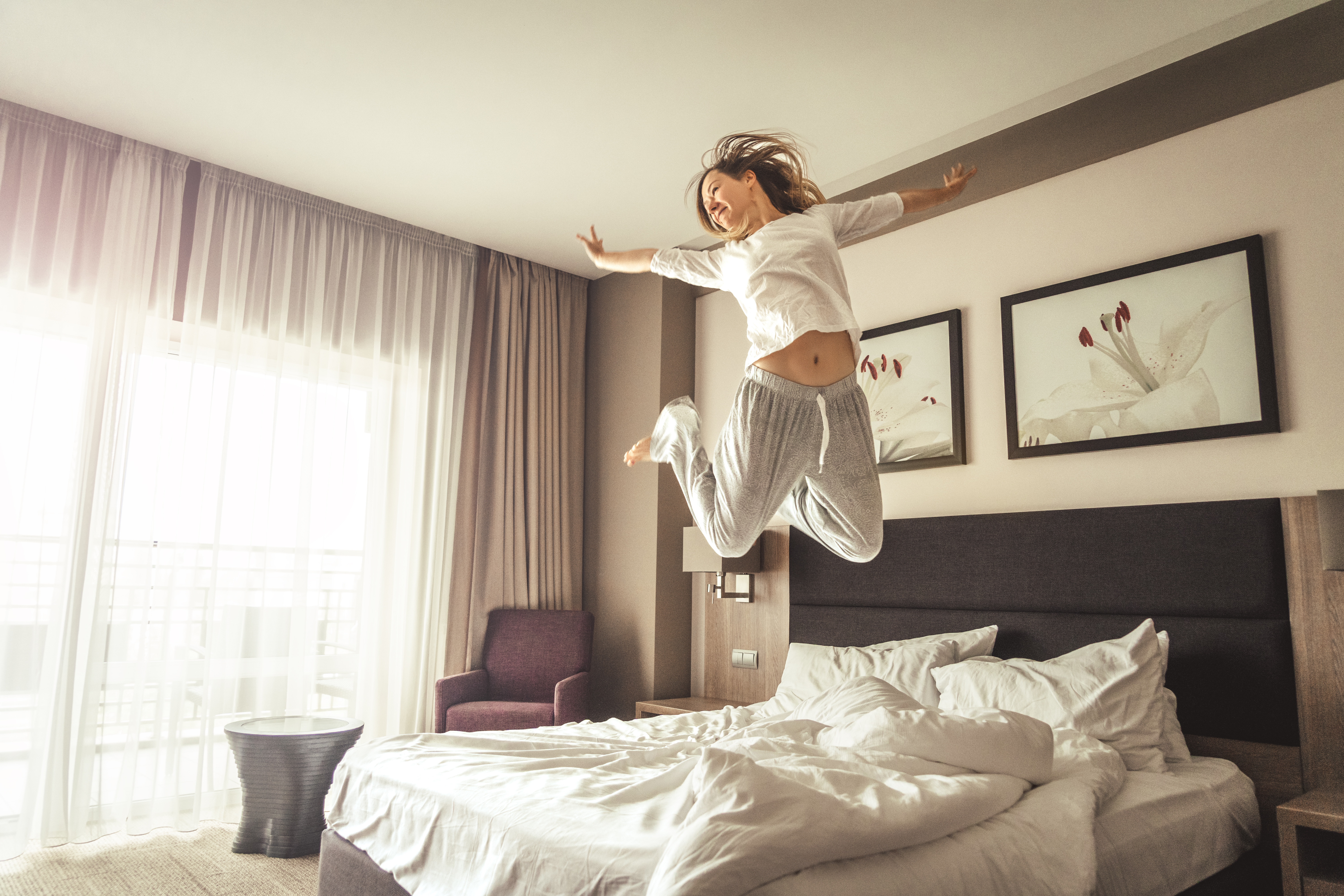 Woman jumping on bed in hotel